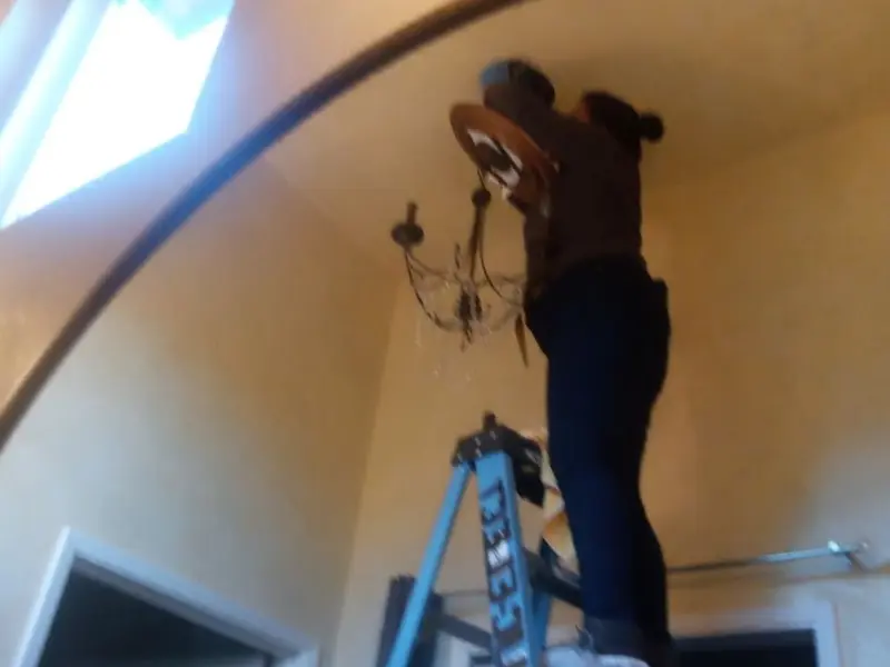 Electrician installing a chandelier in a South Haven residence